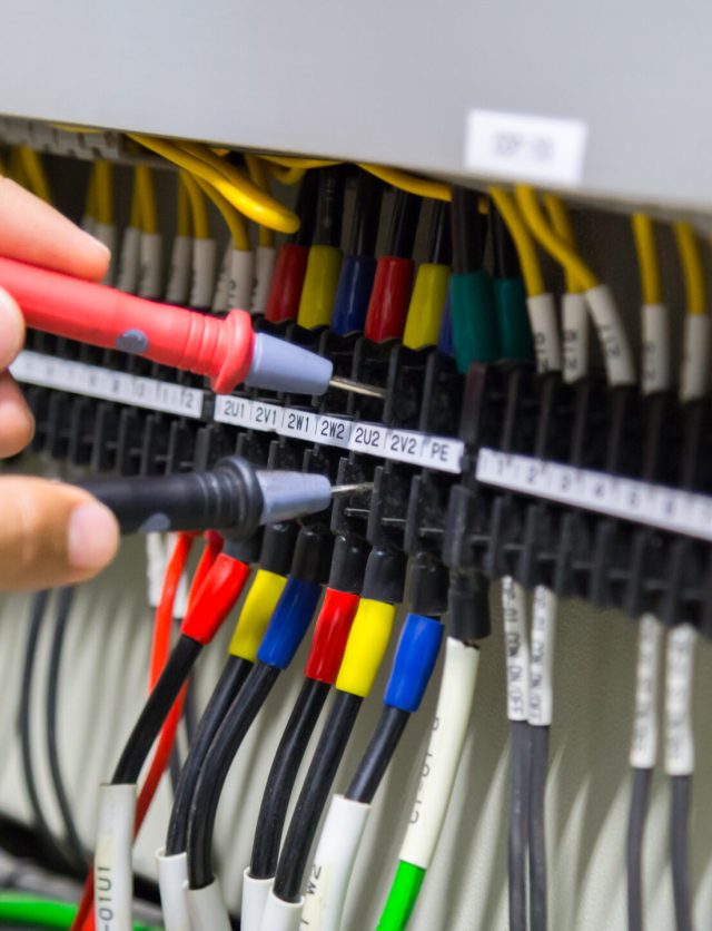 Electricians hands testing current  electric in control panel.